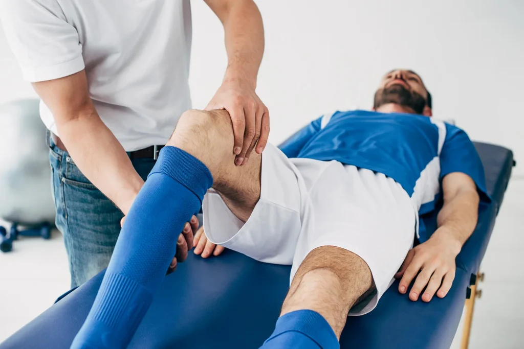 physiotherapist massaging leg of football